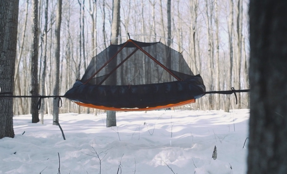 Aerial A1 Tent with optional gear hammock installed between two trees, providing a dry and warm camping experience and protection above the snowy ground!.